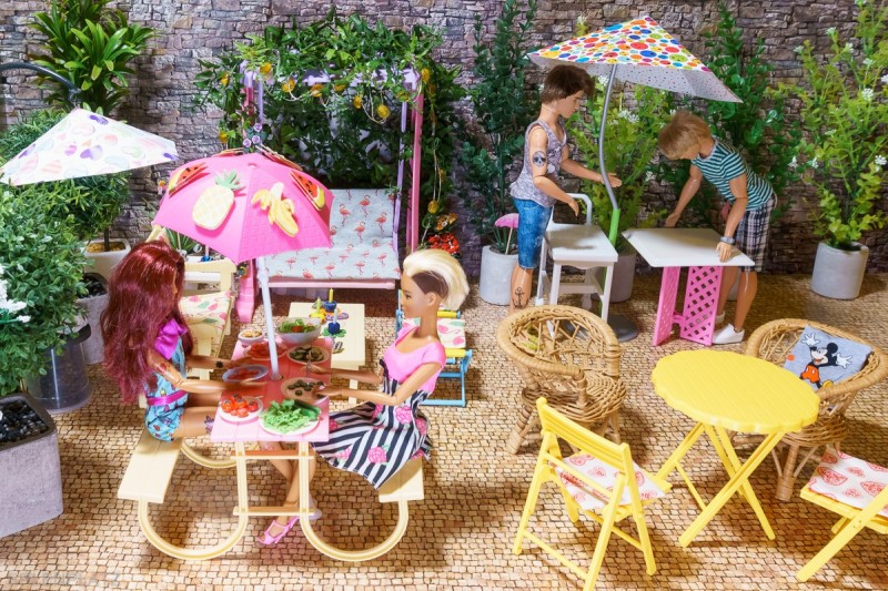 Barbie Julieta und Barbie Gabriela bereiten Tomate, Gurke und Salat vor. Ken Ryan und Ken Thomas stellen Tische auf.